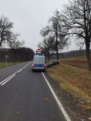 auto w rowie, obok stoi specjalistyczny radiowóz do obsługi wypadków -APRD czyli Ambulans Pogotowia Ruchu Drogowego, który jest wyposażony w sprzęt niezbędny do pracy na miejscach wypadków oraz kolizji.