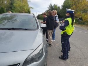 szare auto, dzieci obok a obok policjanta ruchu drogowego w mundurze