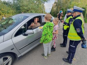 dzieci częstują cytryną kierowcę obok dwie policjantki