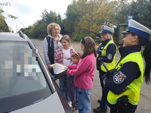 trzy dziewczynki i kobieta stoją obok auta , a przy nich dwie policjantki z wydziału ruchu drogowego w mundurze