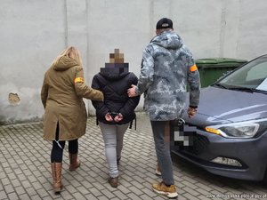 dwoje policjantów prowadzi osobę zatrzymaną