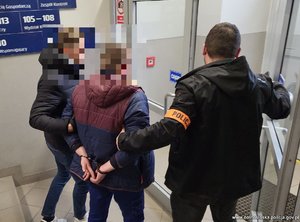 dwóch policjantów prowadzi osobę zatrzymaną