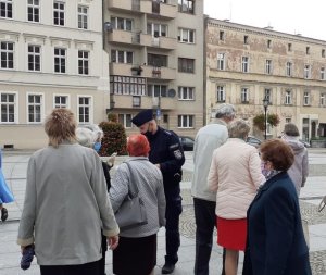 Policjant rozdaje ulotki grupie seniorów na Placu Świętego Jana Pawła II w Świdnicy