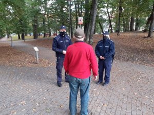 patrol w składzie policjant i policjanta kontrolują spacerowicza co do respektowania przepisów dotyczących Covid19