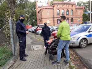 patrol kontroluje mężczyznę z wózkiem z małym dzieckiem, co do przestrzegania przepisów Covid19